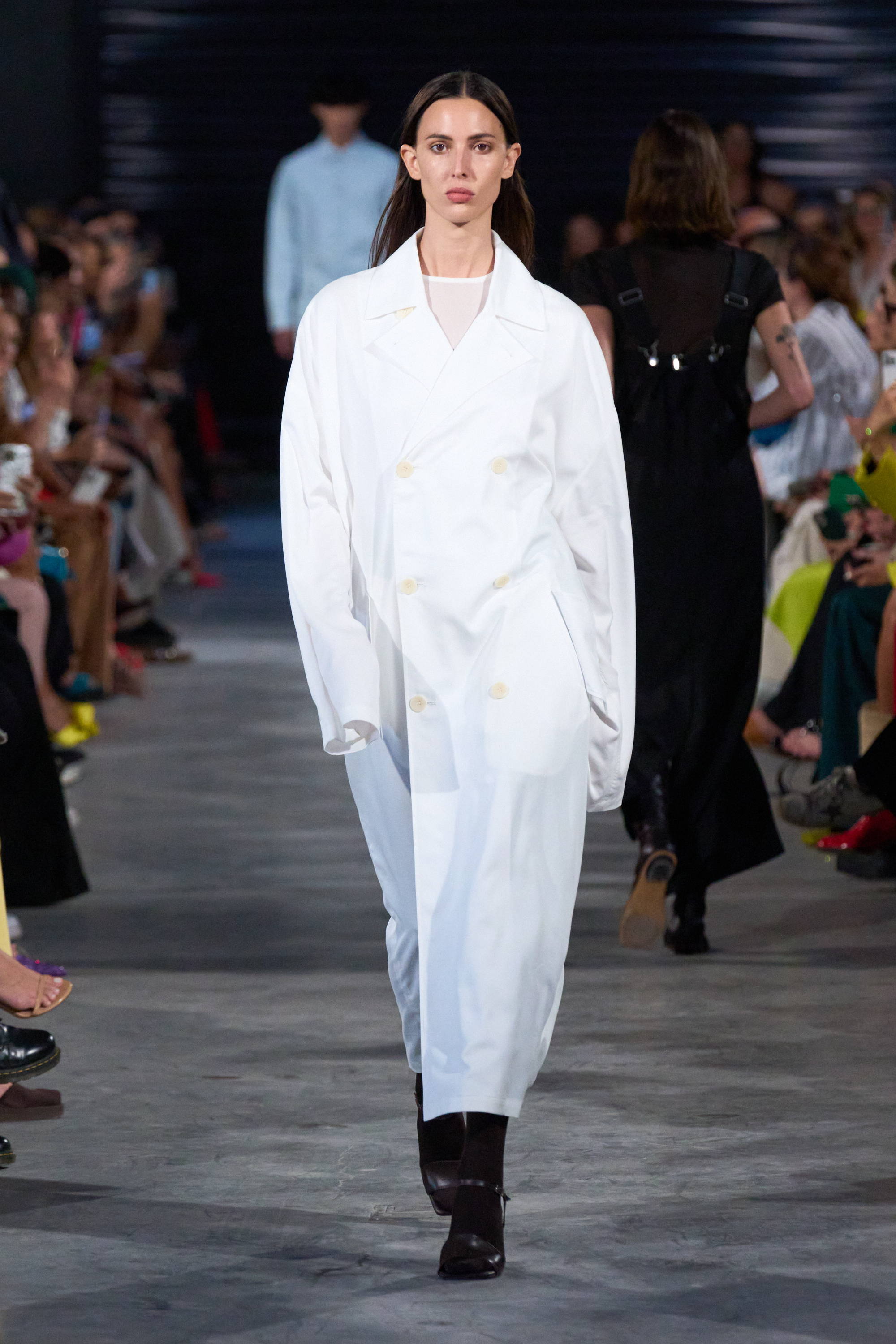 Model on a runway wearing white trench coat