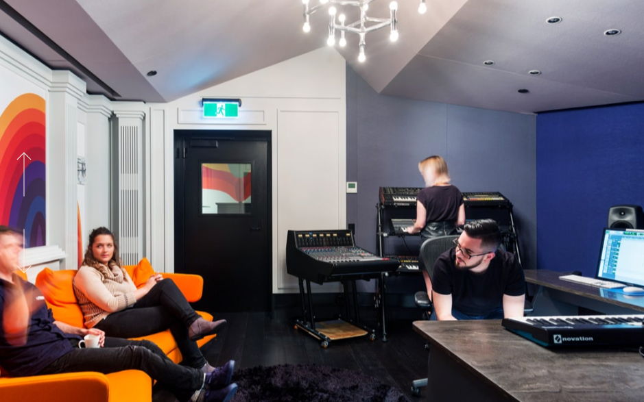 People collaborating in a modern studio with colorful decor and equipment.
