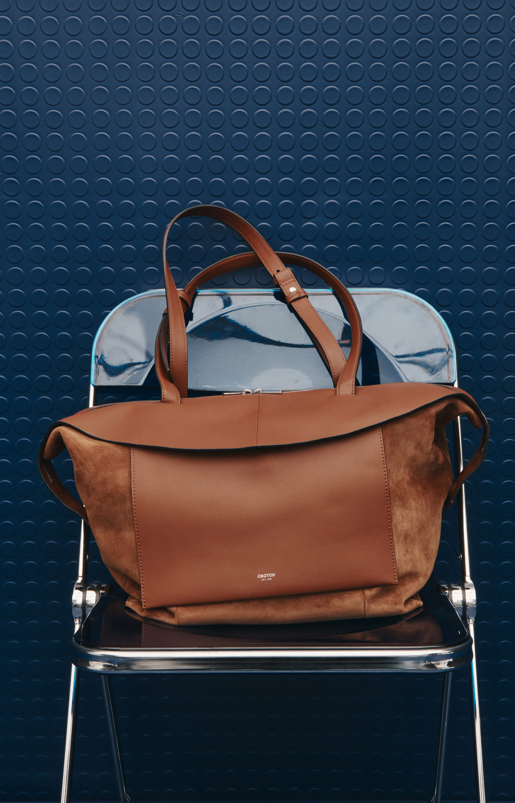 A brown bag placed on a metal chair against a textured blue background.