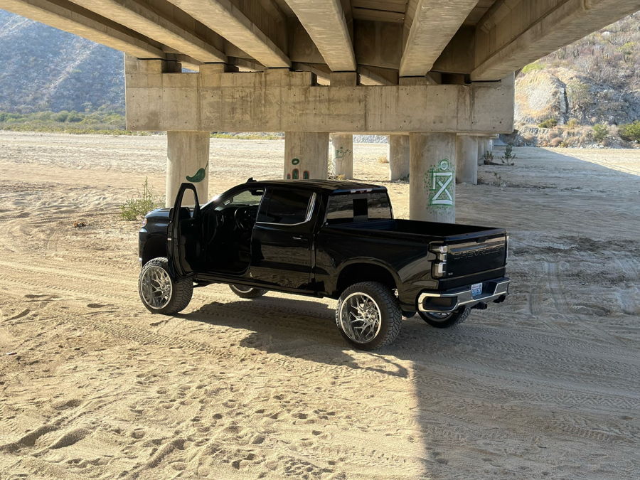 Rear three-quarter view Jimmy's 2020 Chevy Silverado 1500 lifted black truck under bridge Conductor's Special 844 Nightmare Edition HornBlasters featured install gallery photo 1