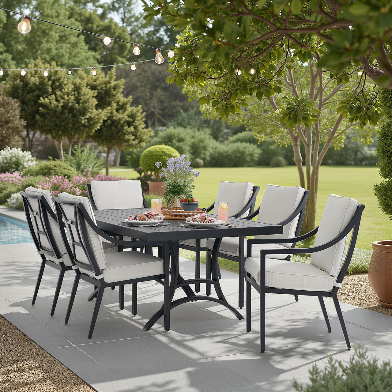 Outdoor dining table with chairs, surrounded by greenery and decorative plants.