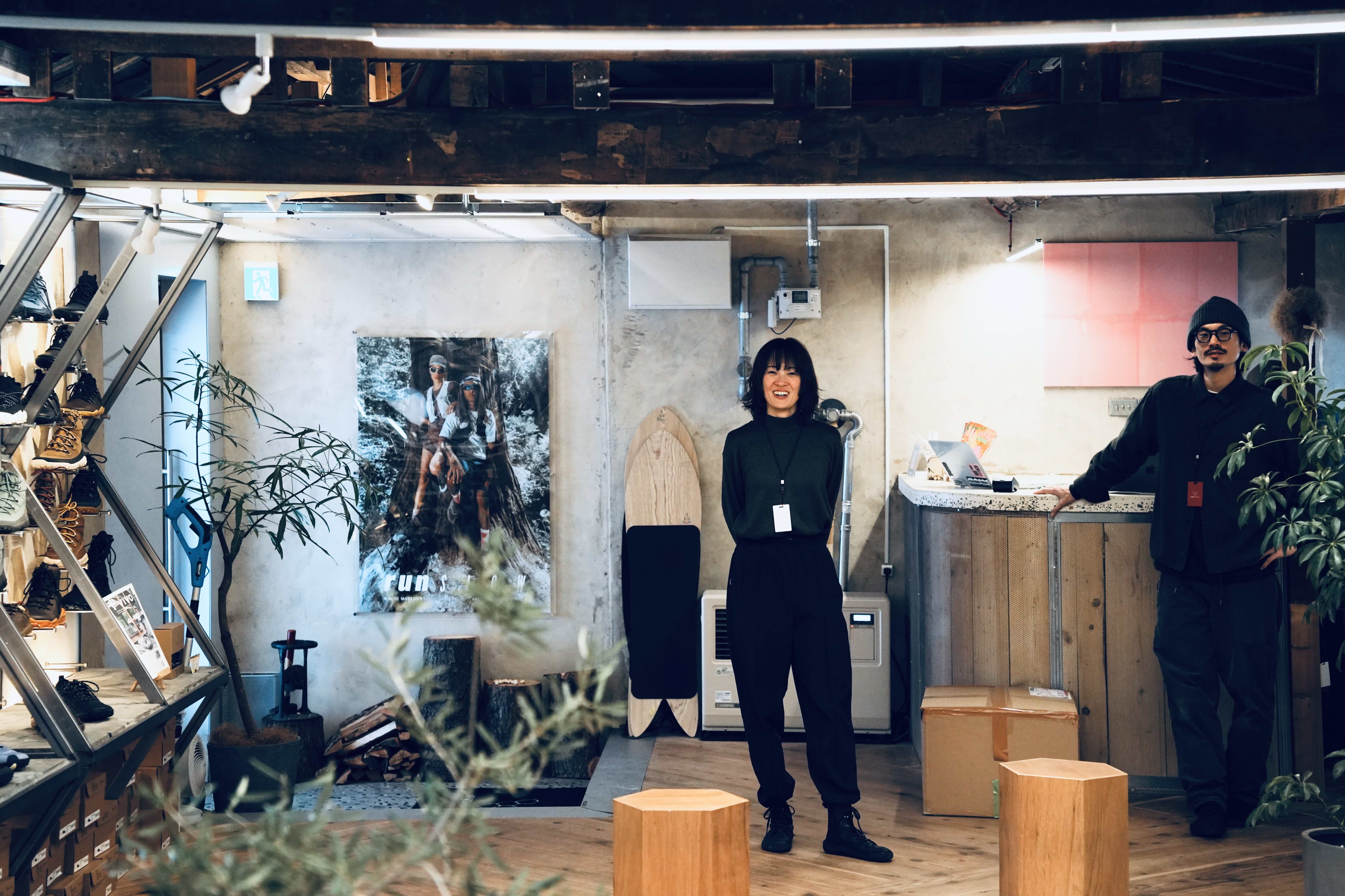 Two people standing in a stylish, modern interior with plants and artwork.