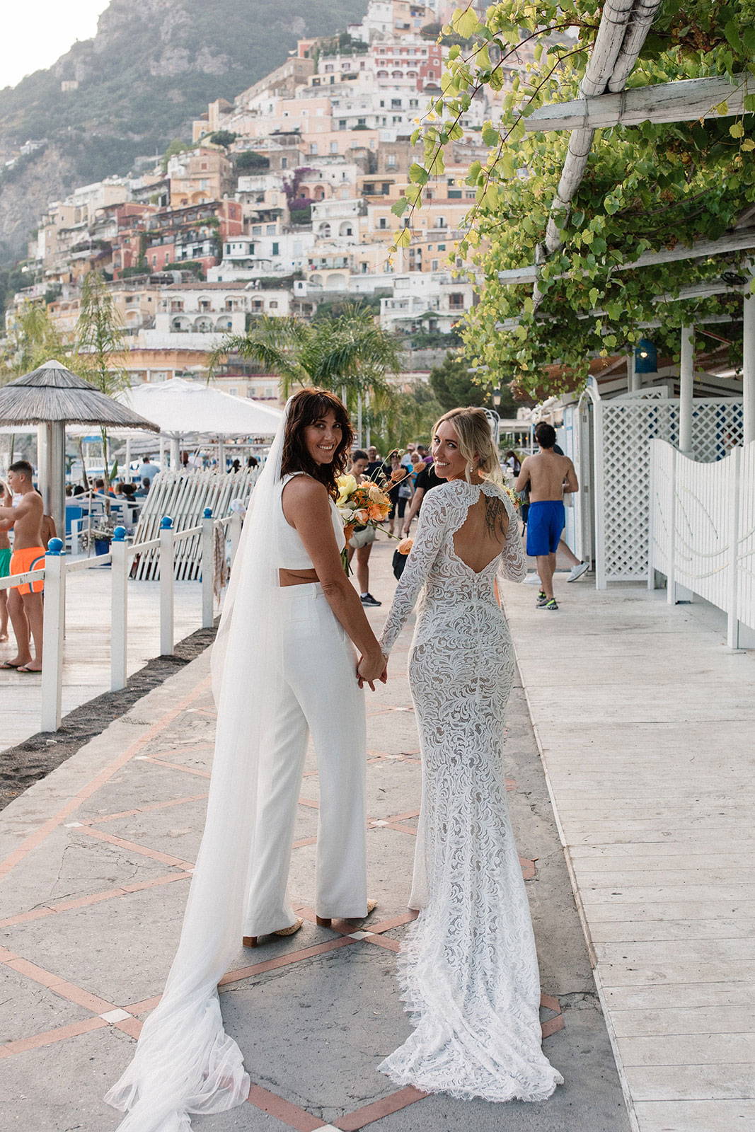 Brides holding hands on walking strip in Italy