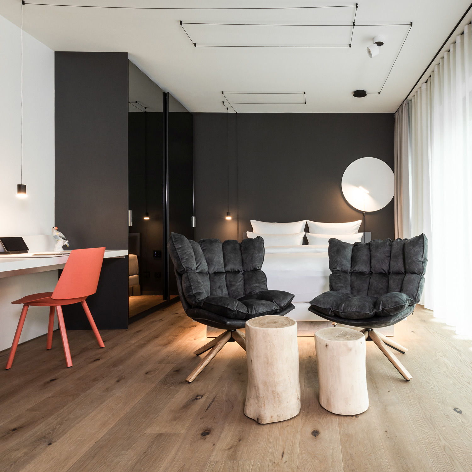 Modernes Schlafzimmer mit zwei Stühlen, Holzhockern und minimalistischer Einrichtung.