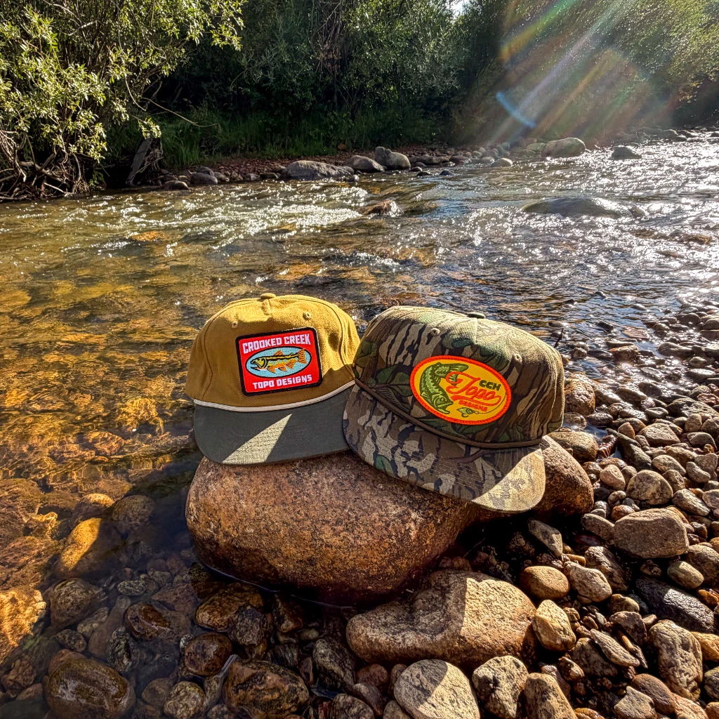 Two hats resting on a rock by a river.