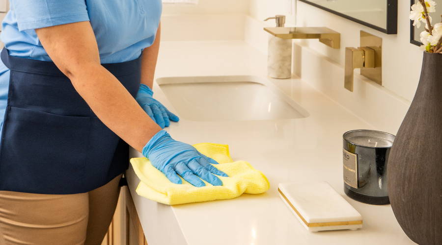 person cleaning counter with microfiber towel