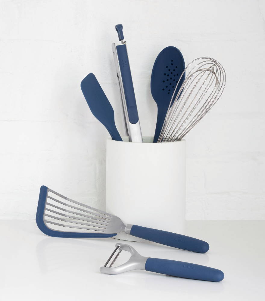 Blue Misen Prep Tools arranged in a white Prep Tool Holder, with a blue Peeler and Fish Spatula laying on the counter nearby.