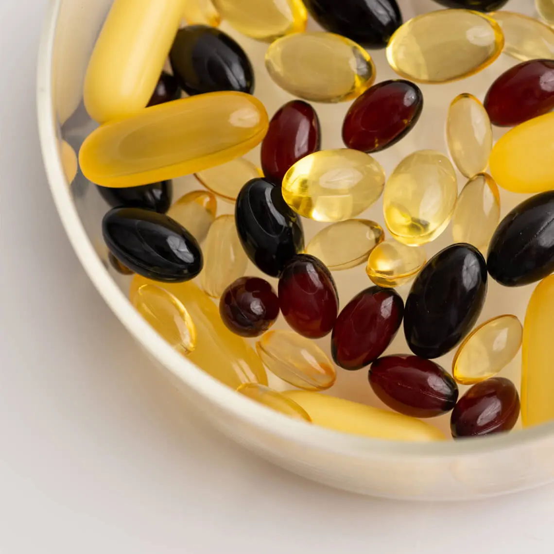 A bowl filled with various colored dietary supplements and gel capsules.