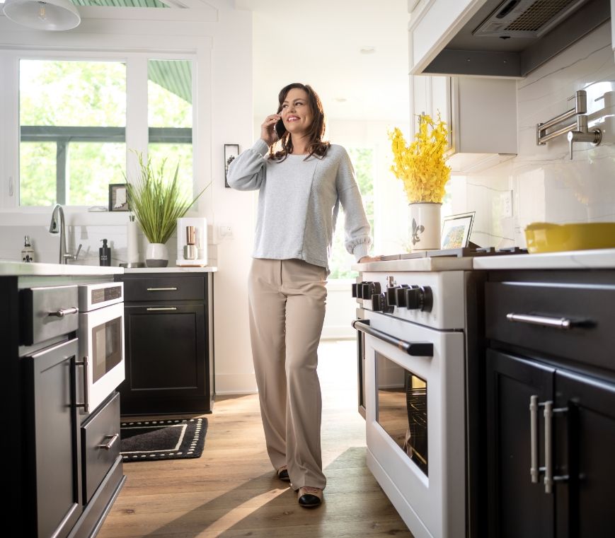 Woman talking on the phone in a modern kitchen with black and white cabinets.