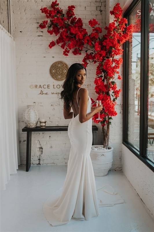 Bride holding champagne wearing the Clo Crepe wedding dress