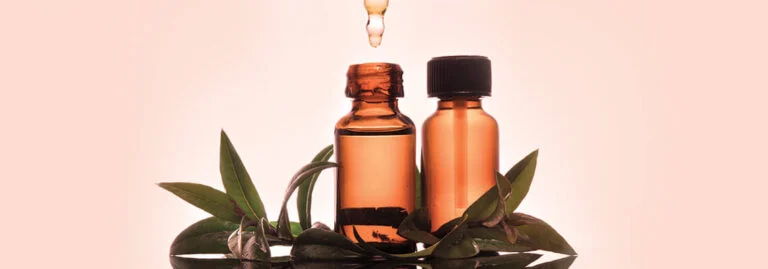 Two amber glass bottles with a dropper, surrounded by green leaves.