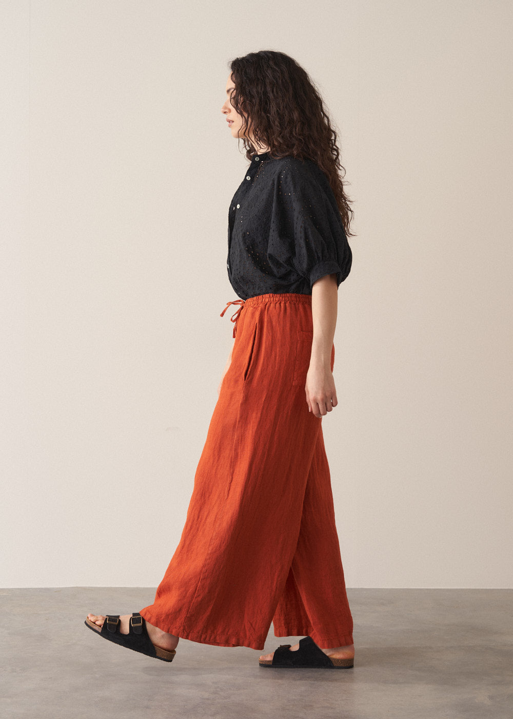 Woman wearing black broderie anglaise top and wide leg red linen trousers