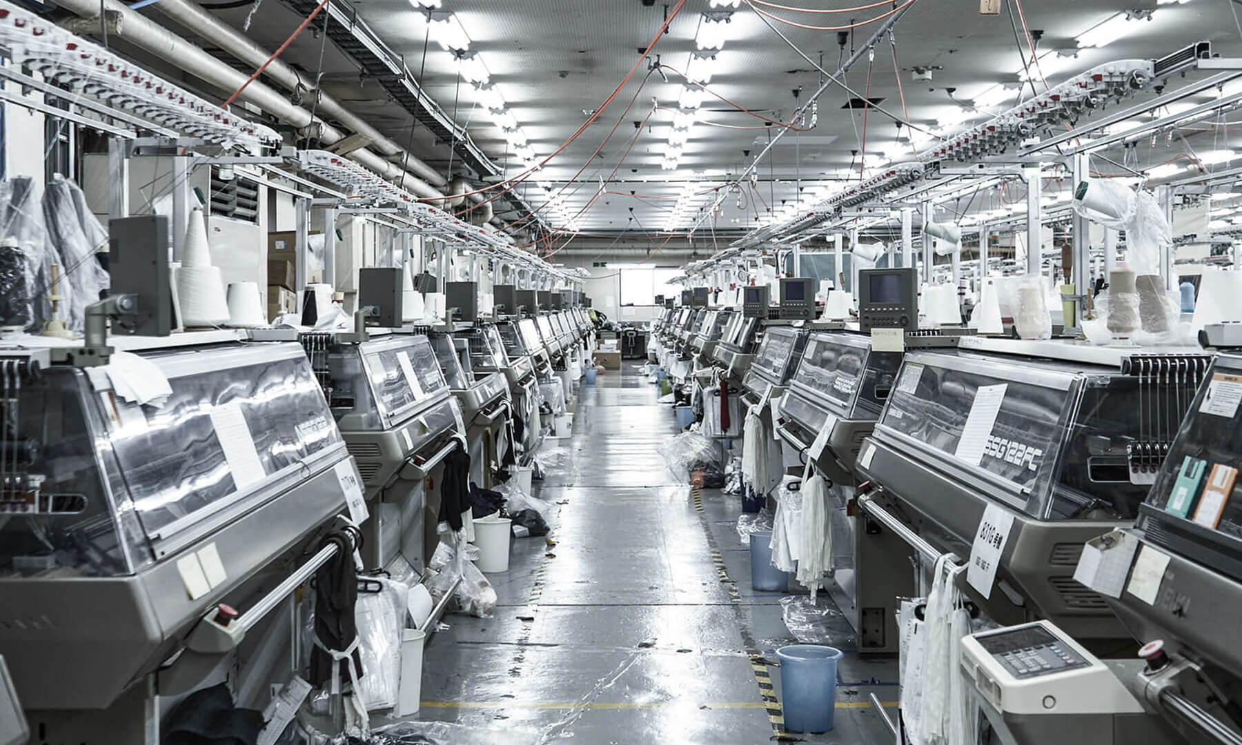 Industrial factory interior with rows of machines and bright overhead lighting.
