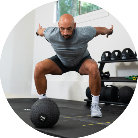 Man exercising with a medicine ball in a gym setting.
