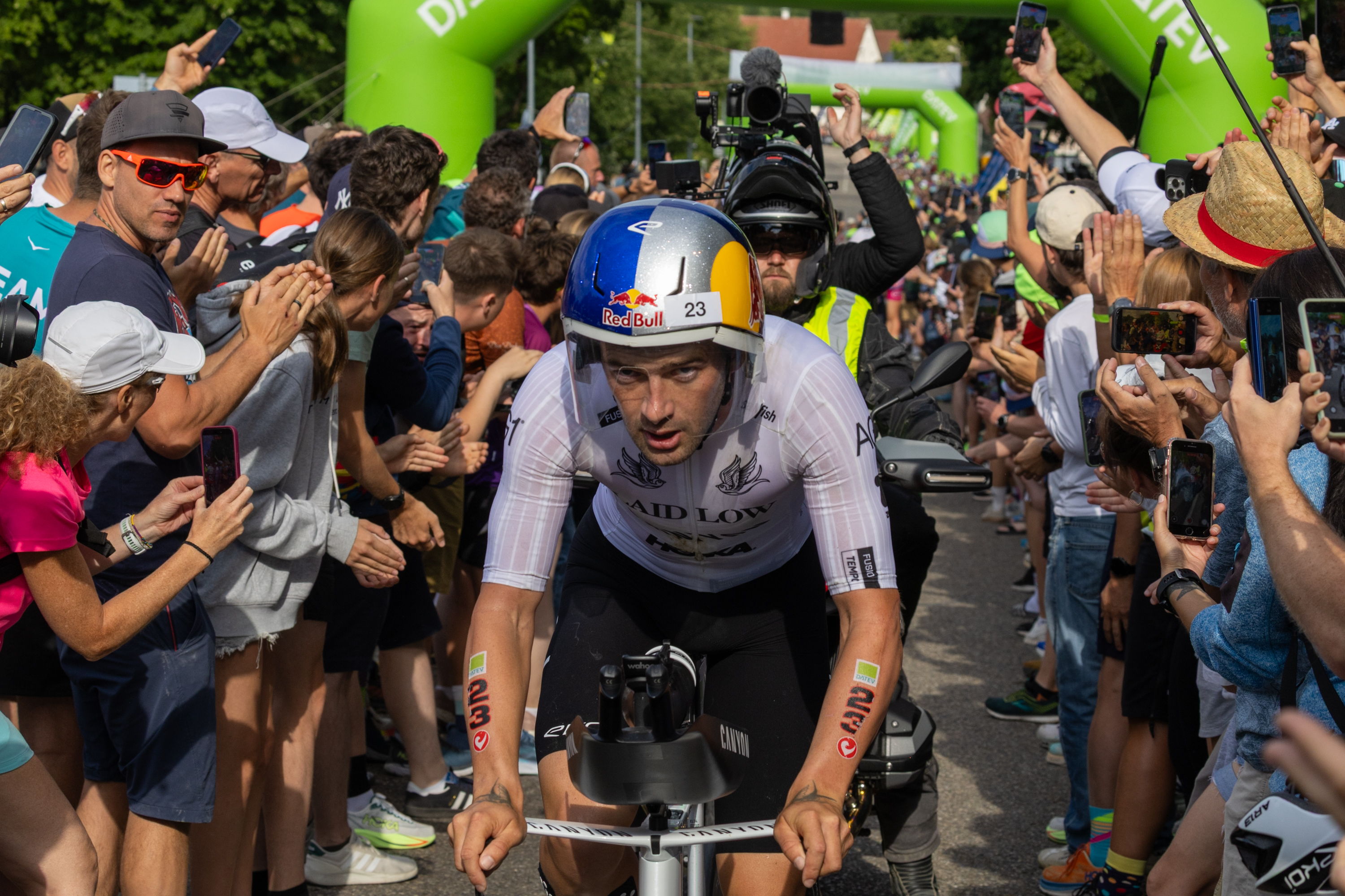 Sam Laidlow bei der Challenge Roth auf der Radstrecke zwischen jubelnden Zuschauern frontal fotografiert.