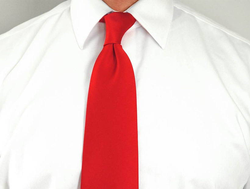 A man wearing a solid red tie with a white dress shirt
