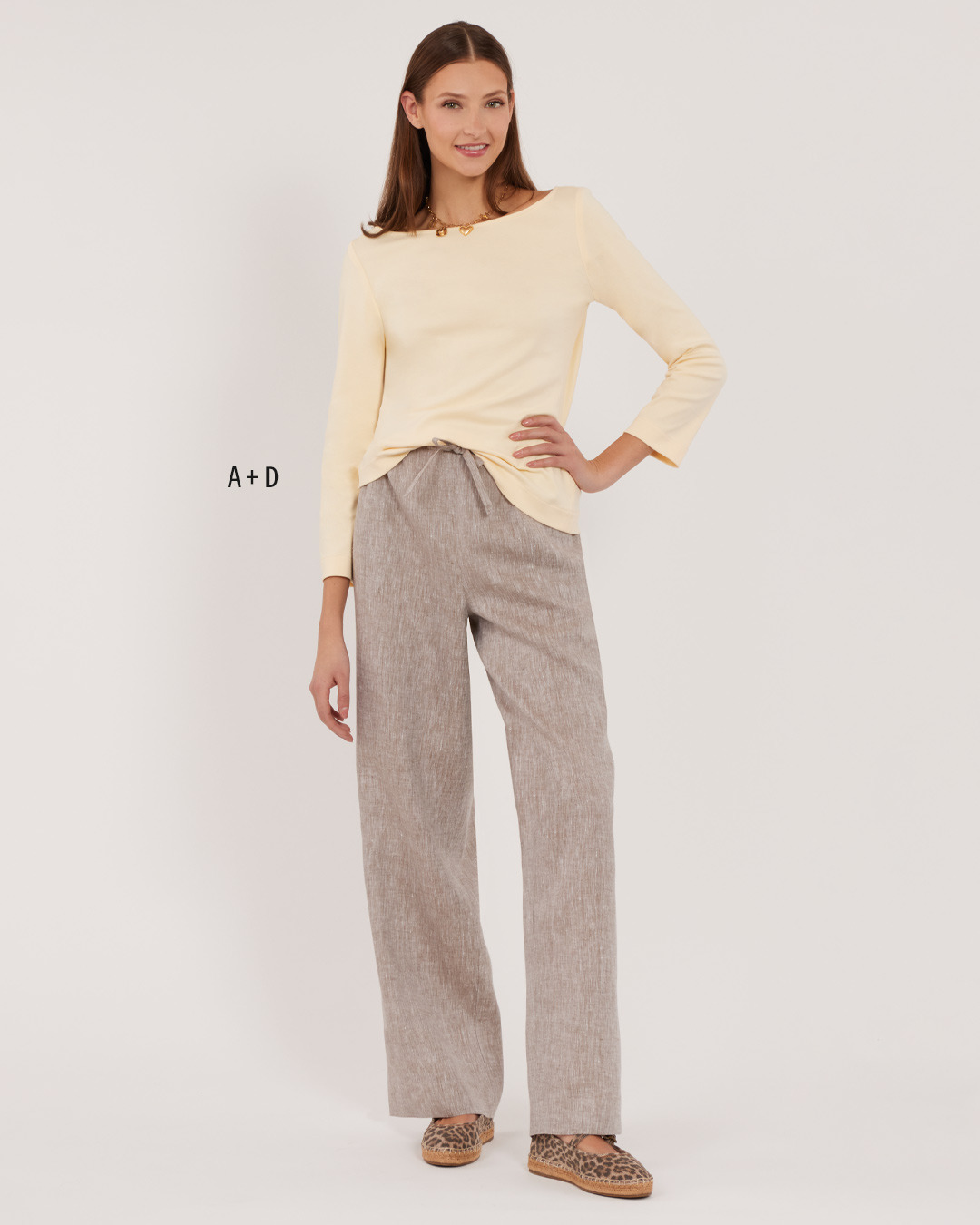 Model wearing a yellow top and beige wide-leg pants against a plain background.