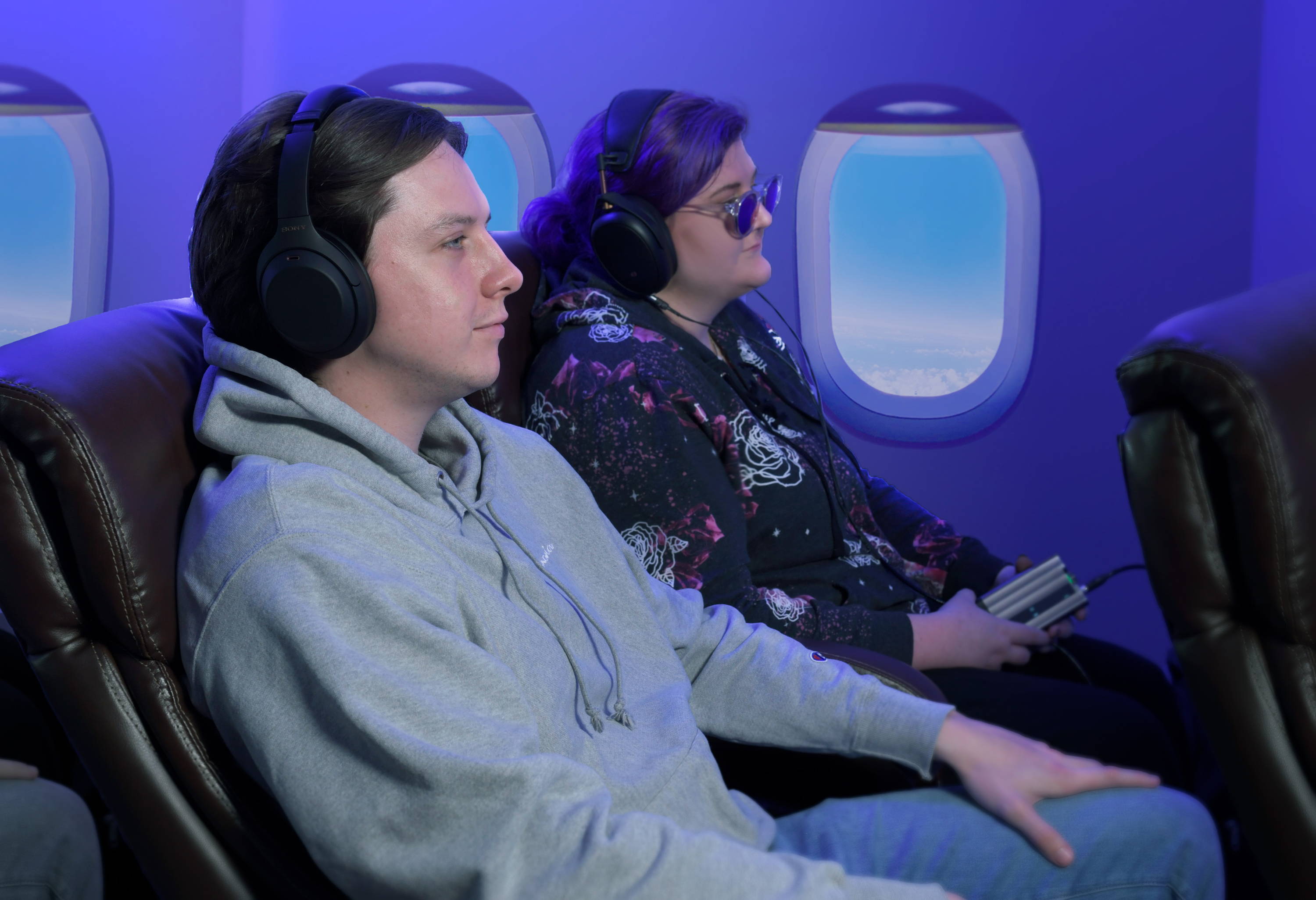 Two people sitting on an airplane with headphones