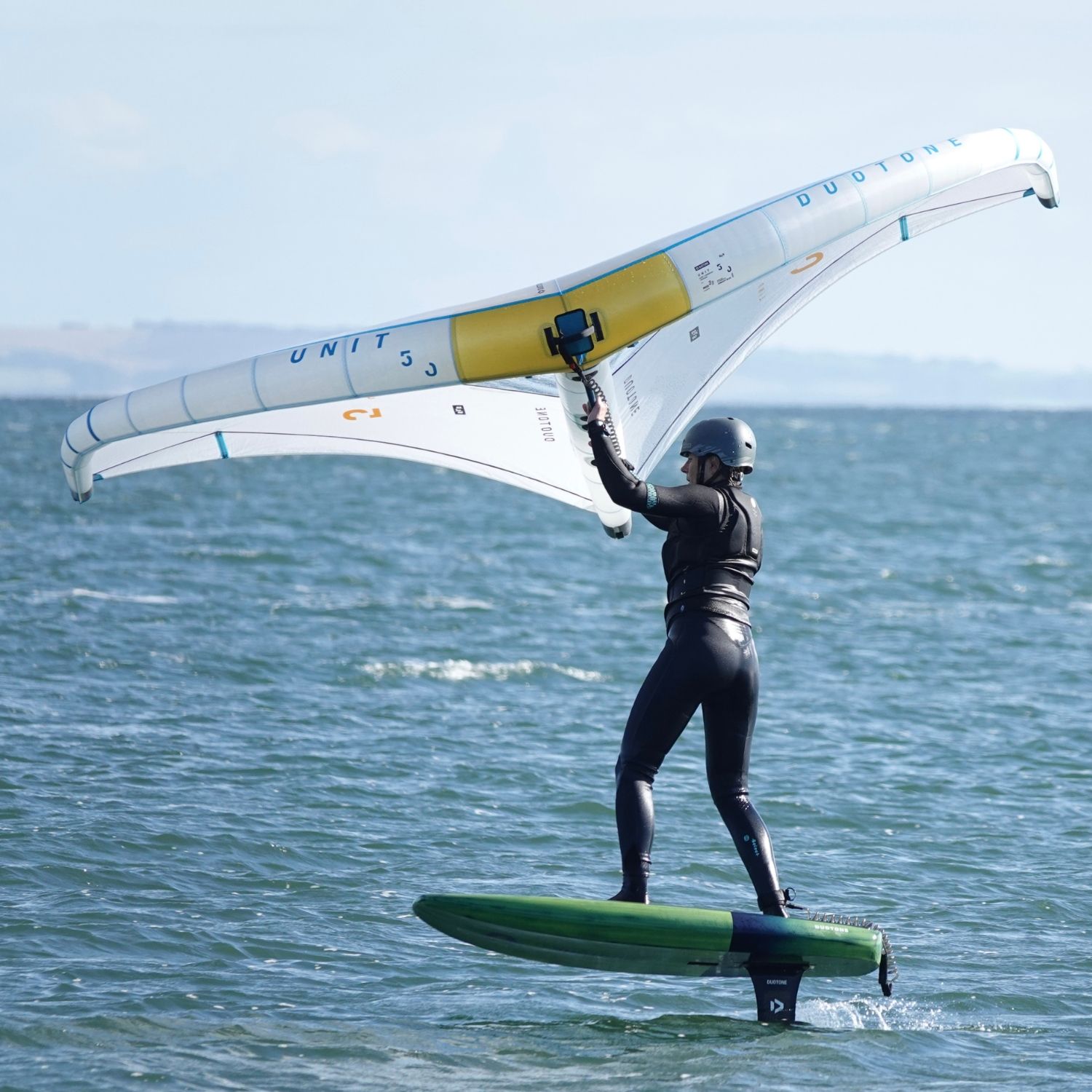 Person surfing on water with a winged foil and wetsuit.