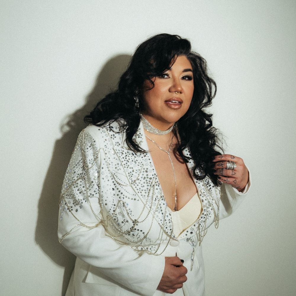 A woman in a stylish white suit poses against a plain background.