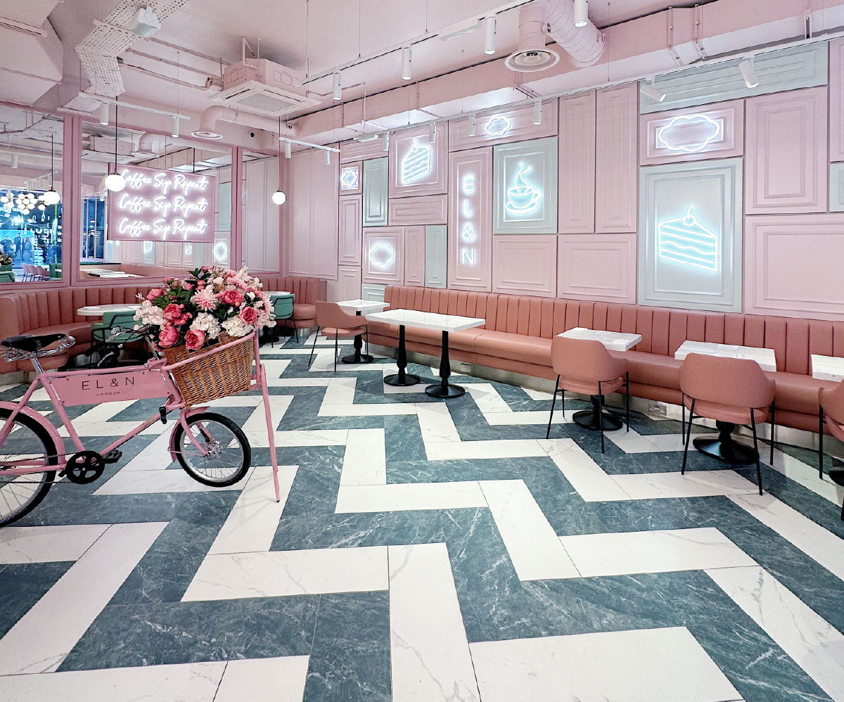 A stylish café interior with pink walls and chevron flooring.