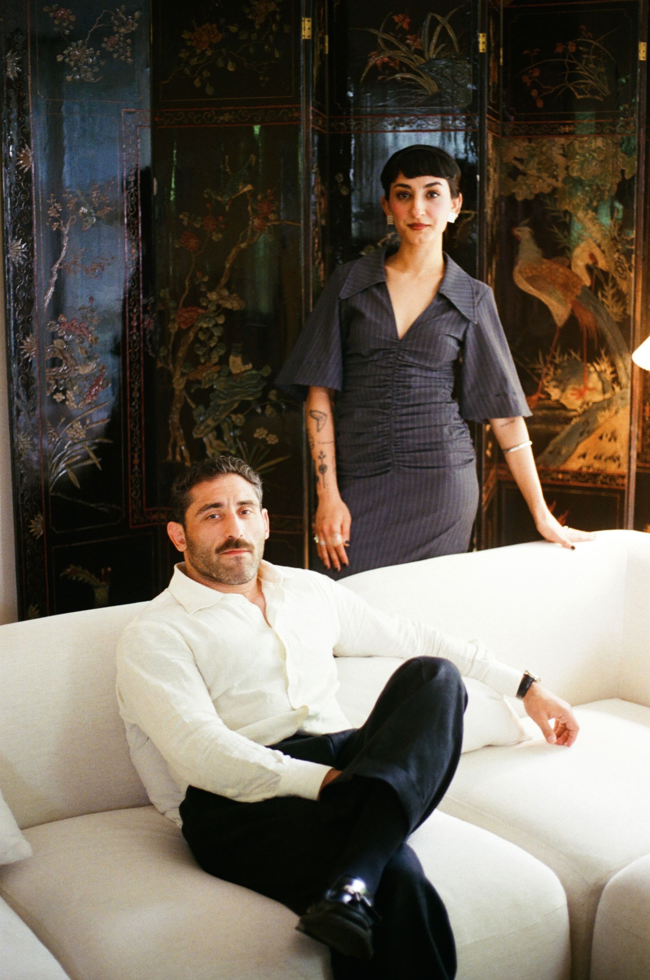 A man and woman posing in a stylish living room.