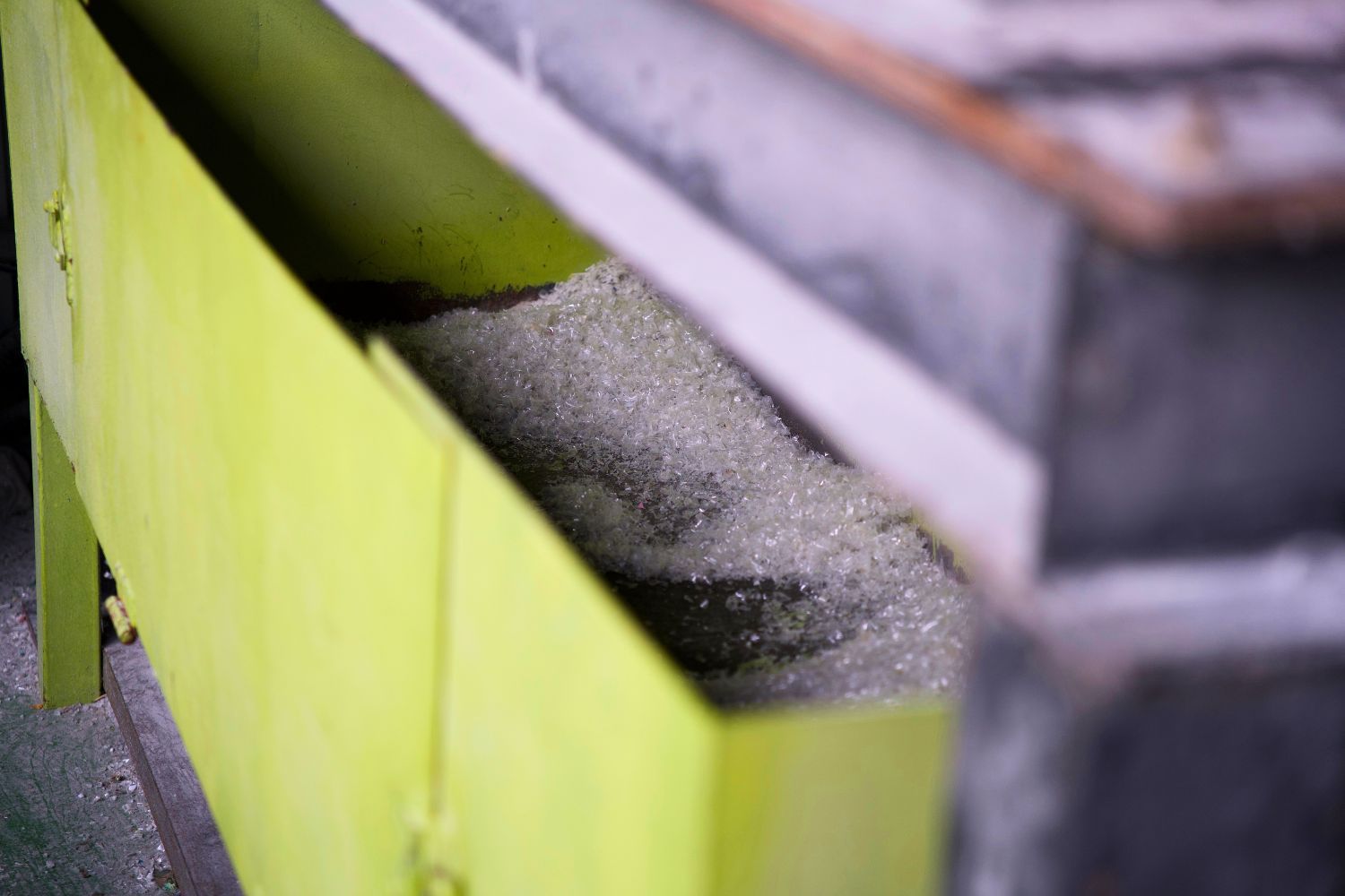 A close-up of a green container filled with sand or gravel.