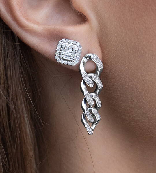 A sterling silver and diamond stud earring and a pave chain earring set in a woman's ear lobe .