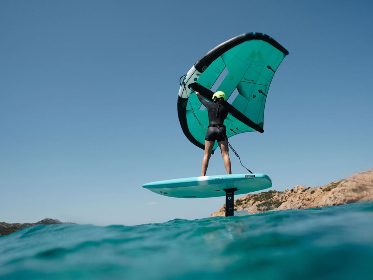 Person on a surfboard using a wing in the ocean.