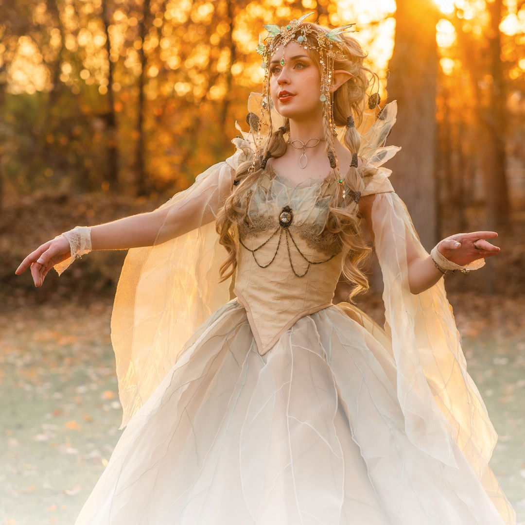 A woman in a flowing dress poses in a sunlit forest.
