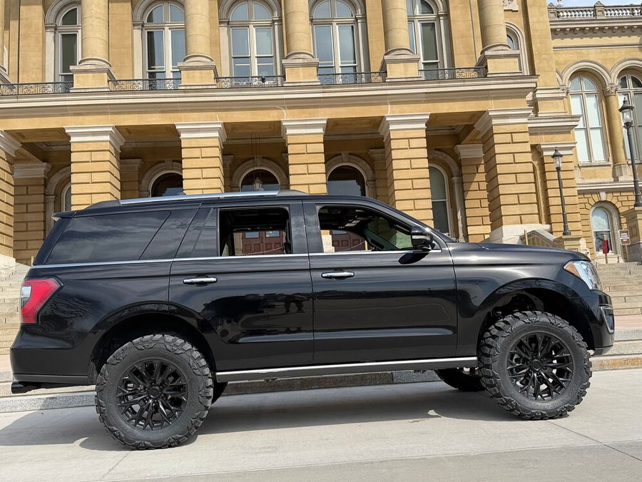 Side profile Troy's black 2018 Ford Expedition with aftermarket wheels before grand building with columns and arched windows gallery photo 7