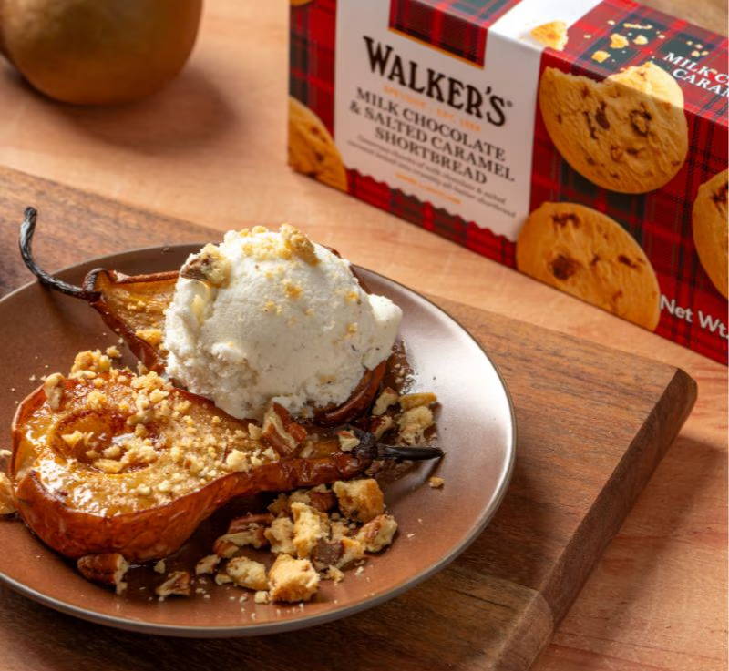 Baked pear with ice cream and cookie crumbs on a plate.