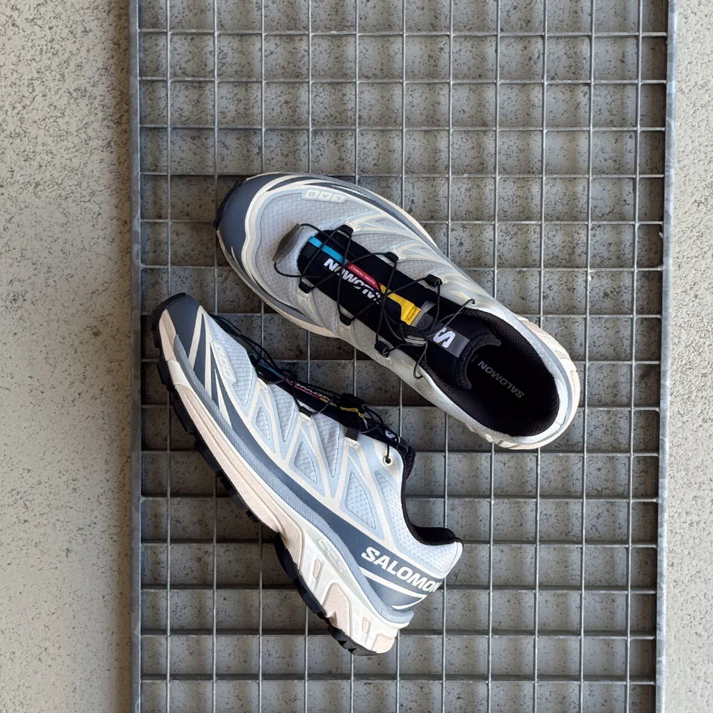A pair of gray and white athletic shoes on a textured surface.