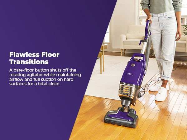 Person using a purple vacuum cleaner on wooden floors.