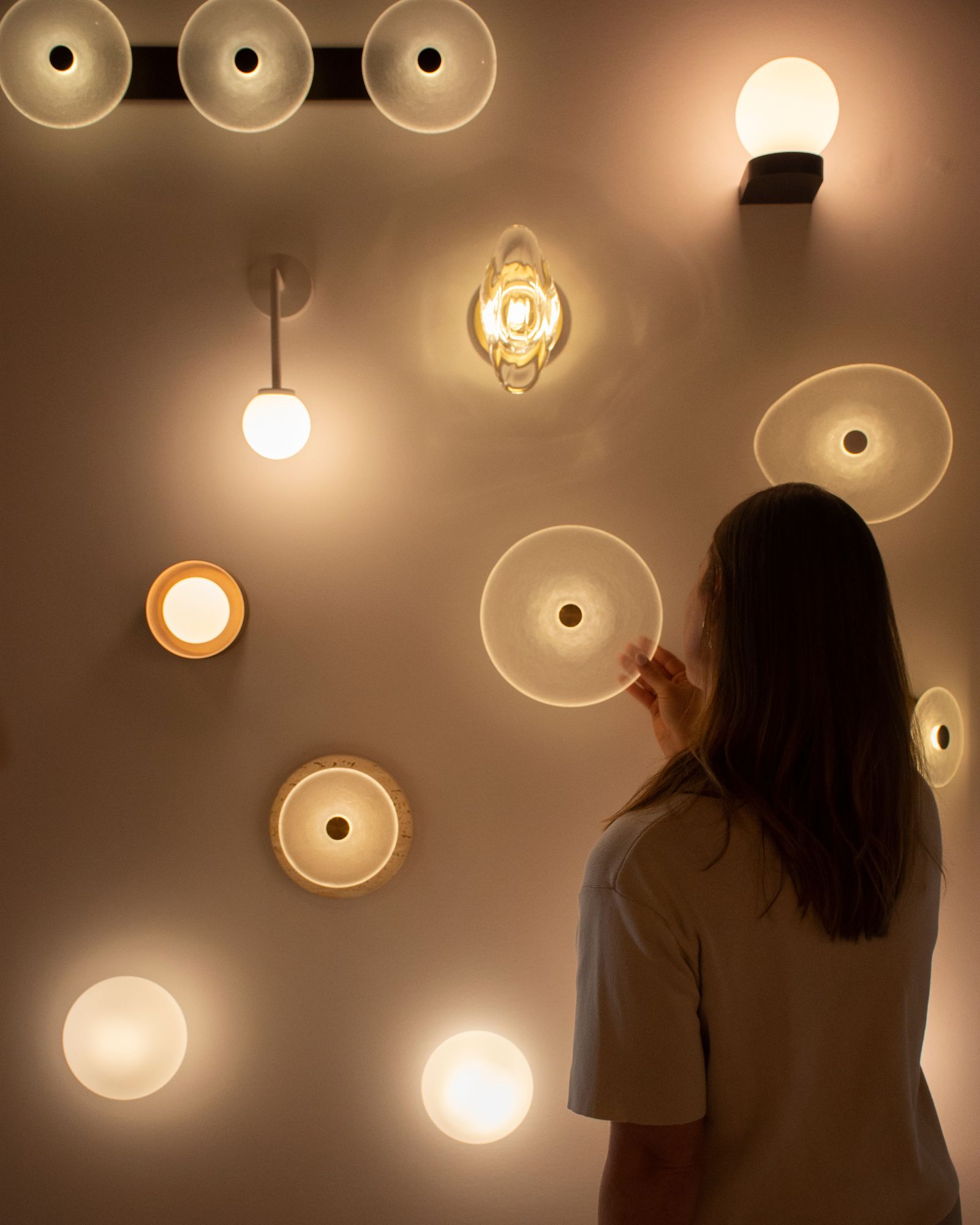Person interacting with various light fixtures on a wall.