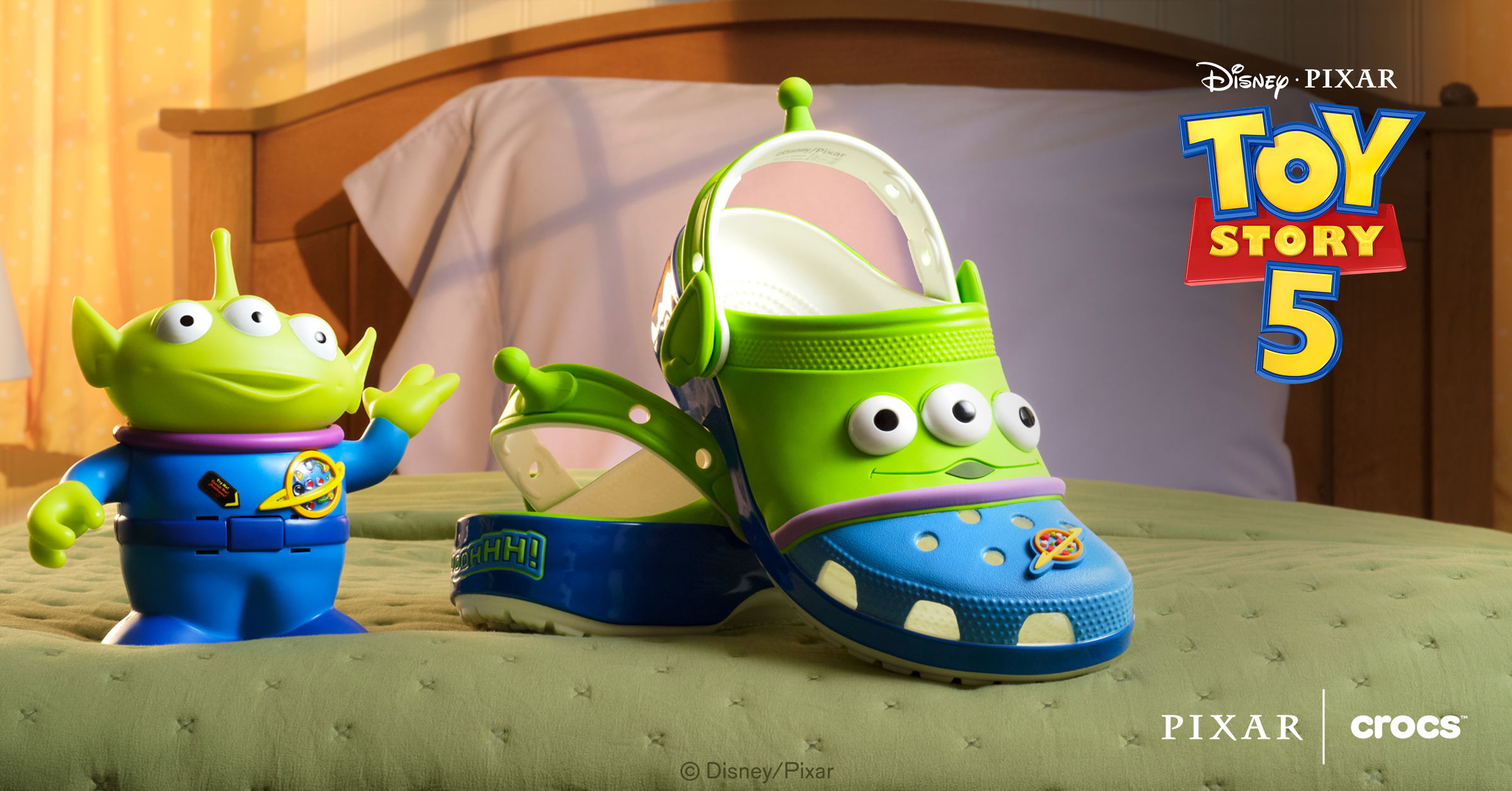 Toy Story 5 themed shoes and alien toy on a bed.