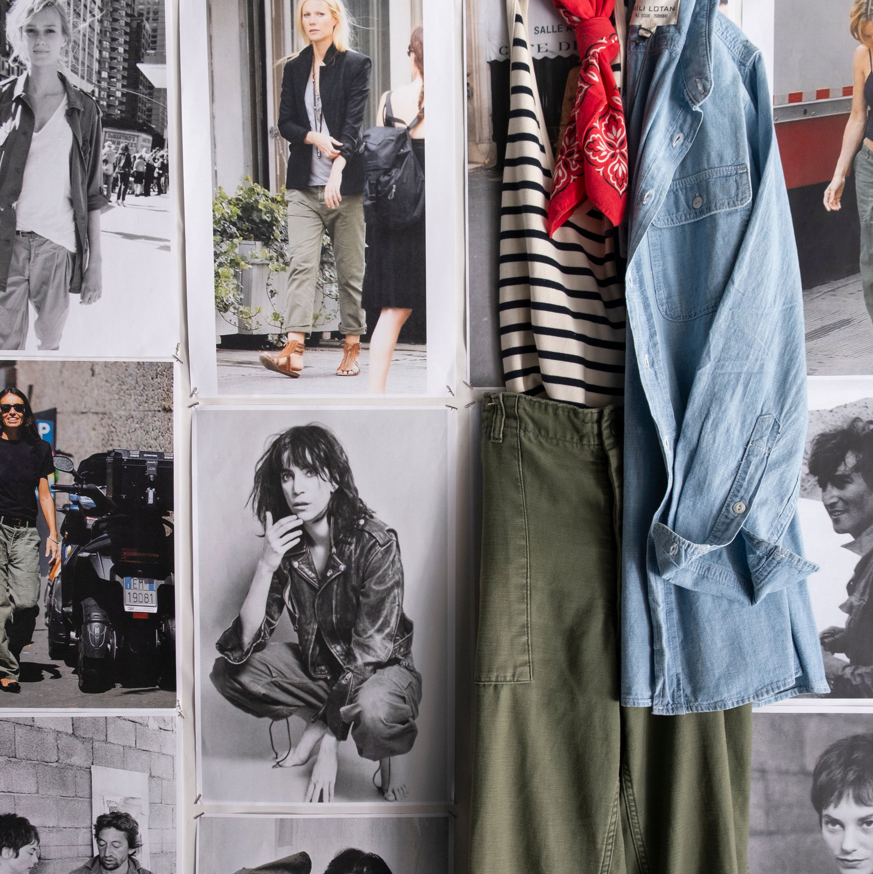 Clothes hanging on a wall with black-and-white fashion photos in the background.