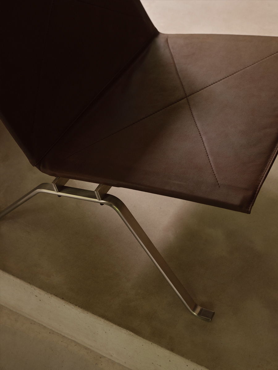 Brown PK22 Fritz Hansen chair with a sleek metallic frame on a light surface.