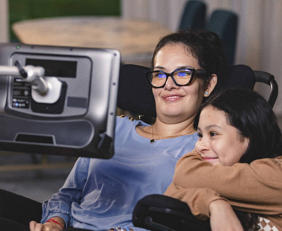 Two women, one in a wheelchair, sharing a moment while using technology.