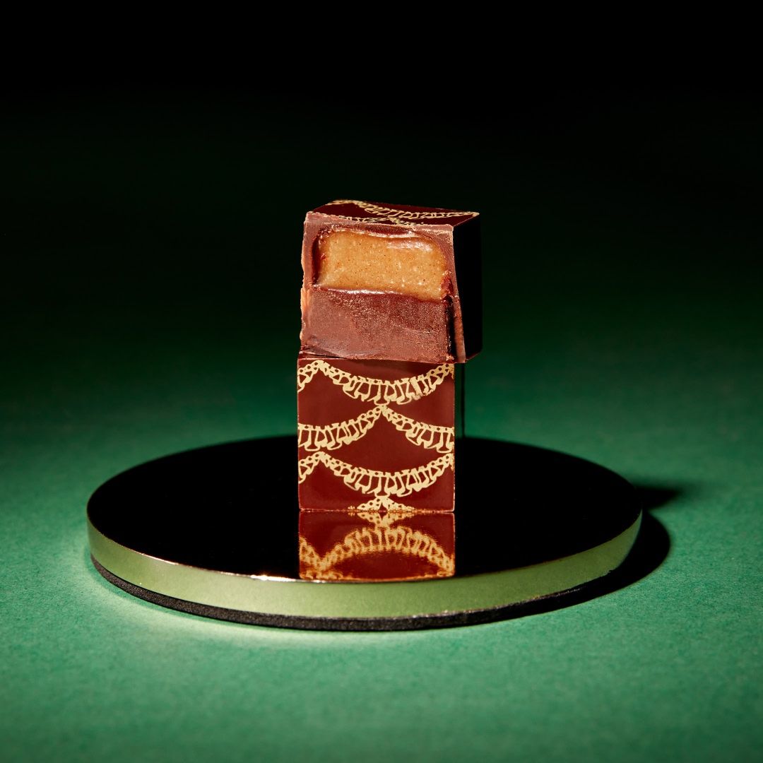 A small chocolate box with decorative patterns on a circular base.