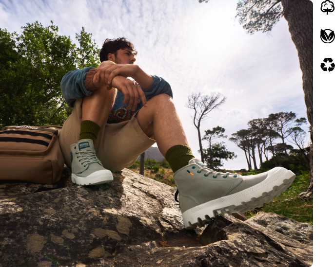 man wearing green canvas boot with white sole  sitting on a rock