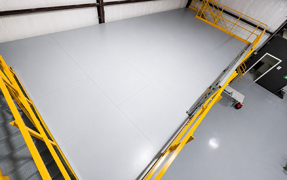 Aerial view of a gray floor with yellow scaffolding.