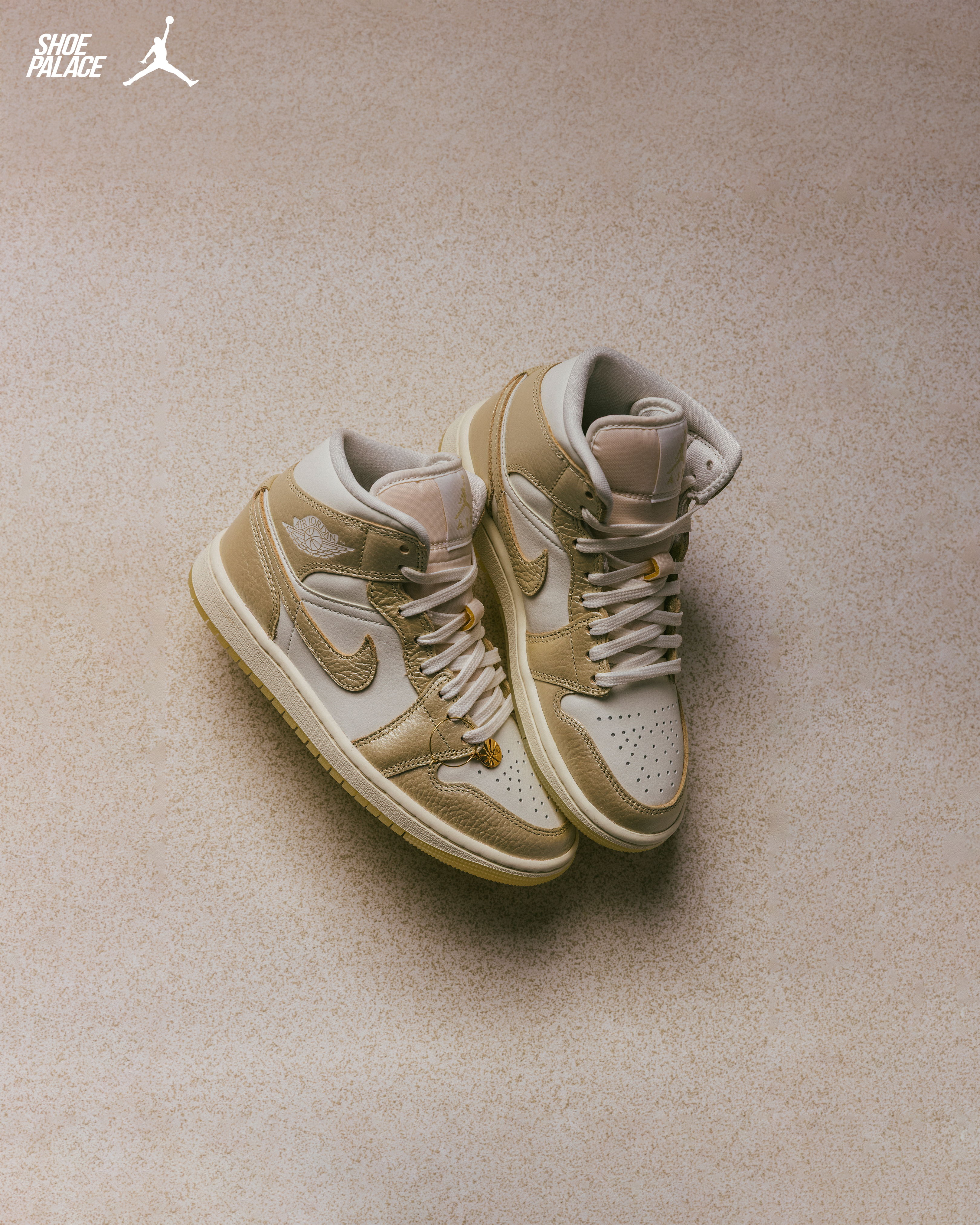 A pair of beige and white sneakers on a textured surface.