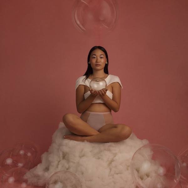 Fotografia de mulher sentada de pernas cruzadas com globo de vidro na mão