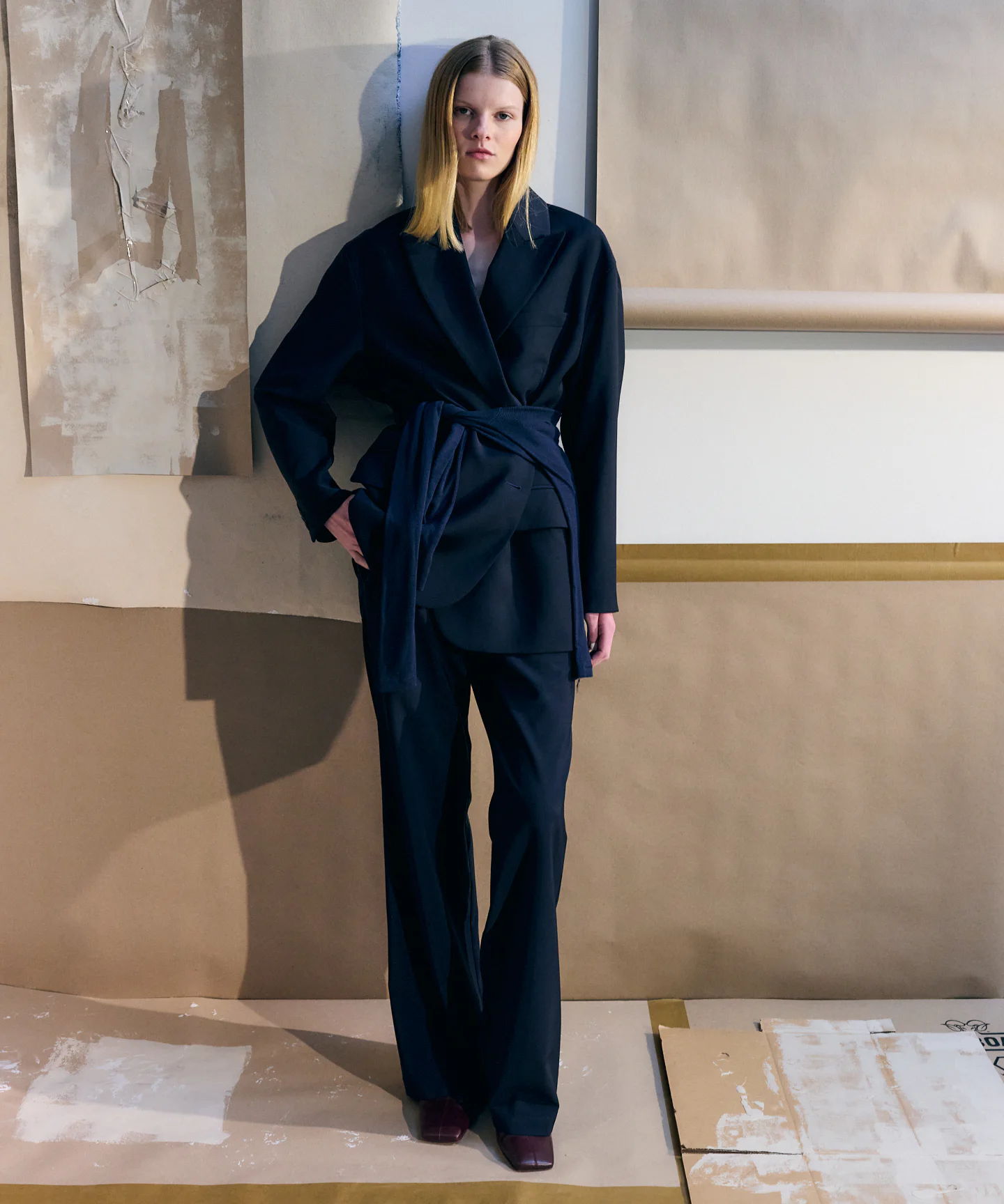 Model wearing a stylish black outfit stands against a neutral background.