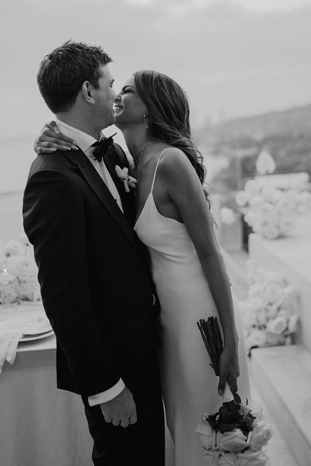 The bride and groom are captured in a moment of pure joy, sharing a heartfelt laugh together