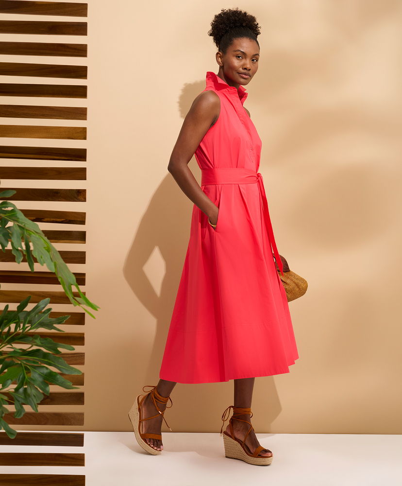 A woman in a pink dress poses against a neutral background.