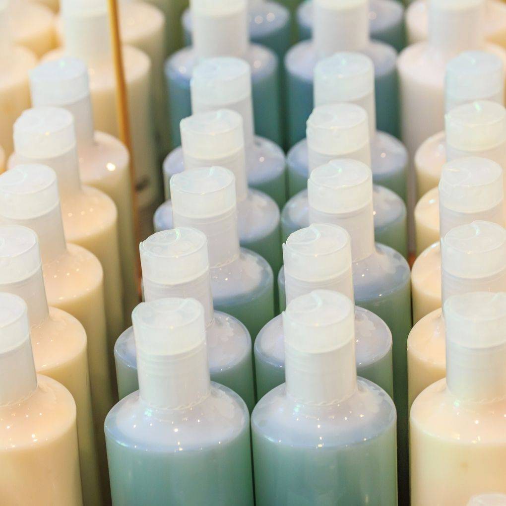 Four rows of beige and blue shampoo plastic bottles
