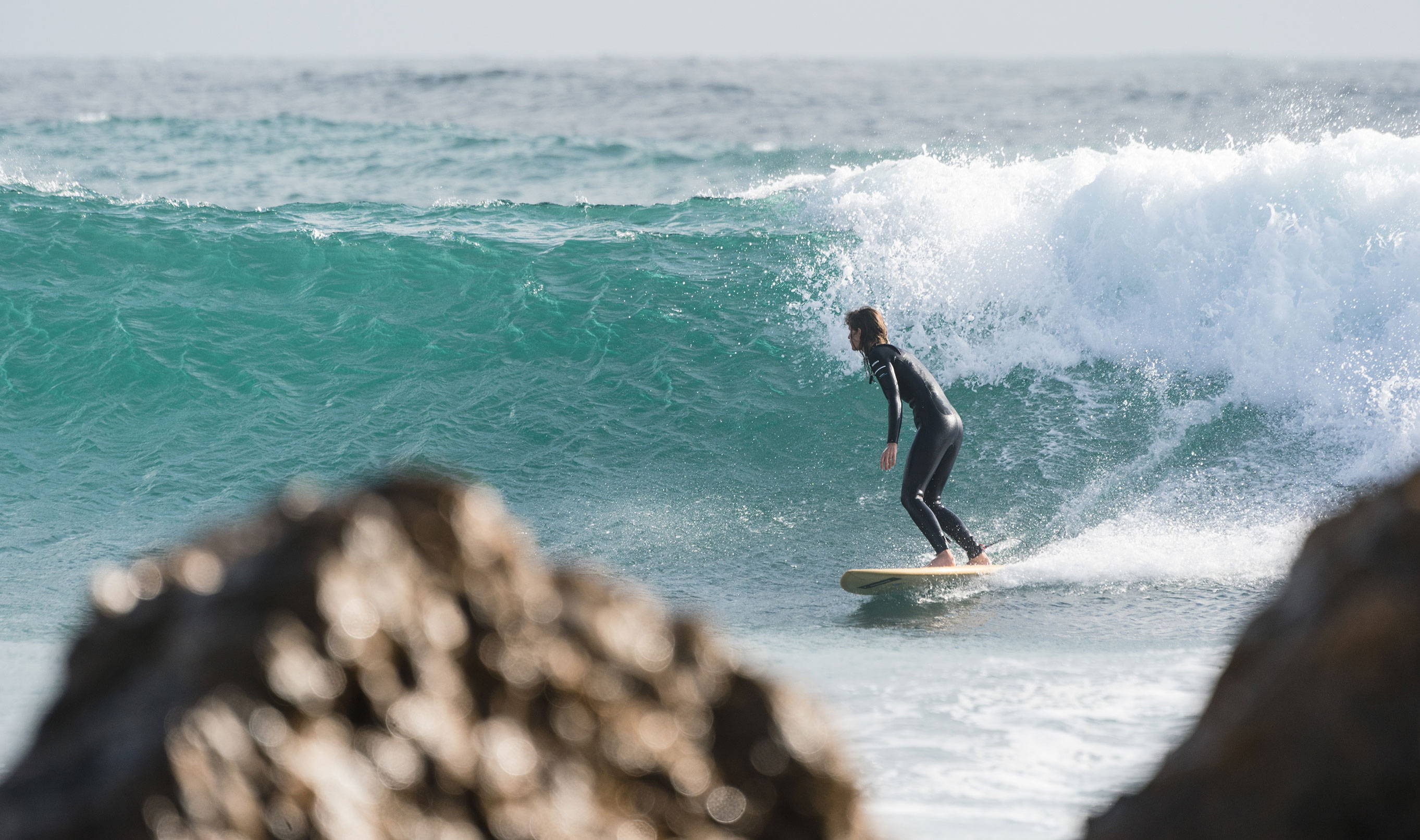 Sally McGee surfing in a Finisterre wetsuit