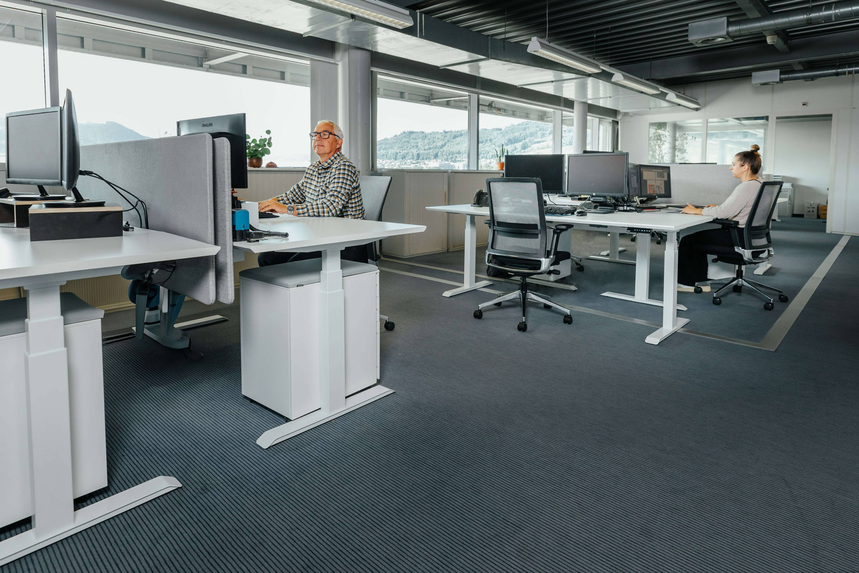 Customer Success Stories - Bern Belp Airport. Two employees are sitting in their bright and modern office, furnished by ofinto